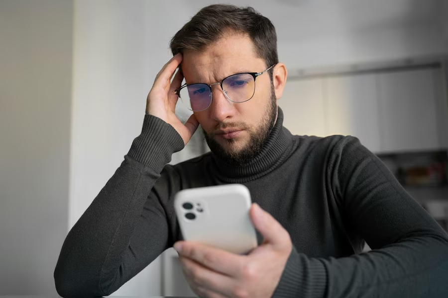  A man holding a phone while holding his head with the other hand