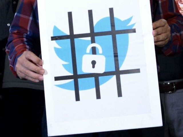 A man holds a picture of a tweeter icon in a cage