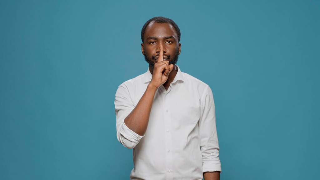 Person making a silent hand gesture with a finger on his lips