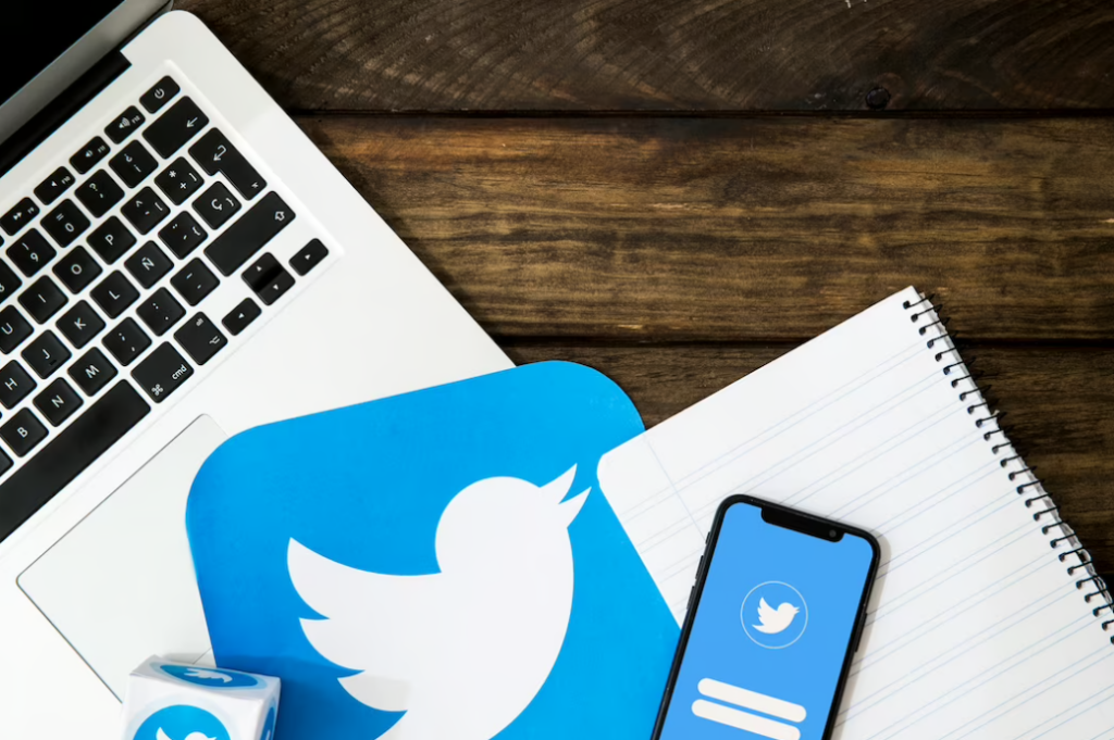laptop, notebook, Twitter logo and phone with Twitter app on it