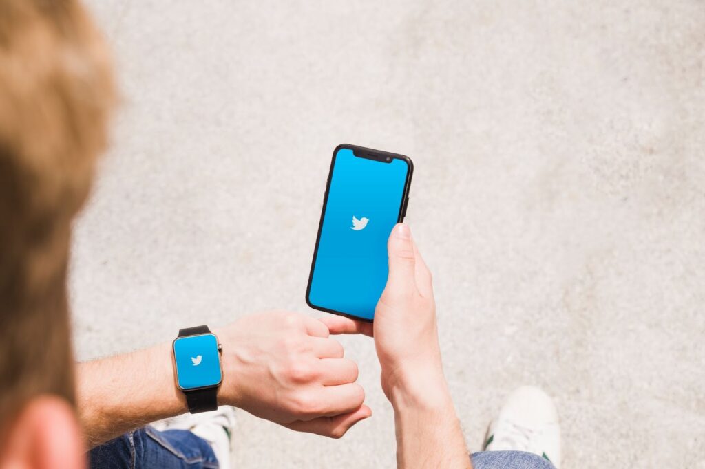 Man with smartwatch and cellphone showing twitter app